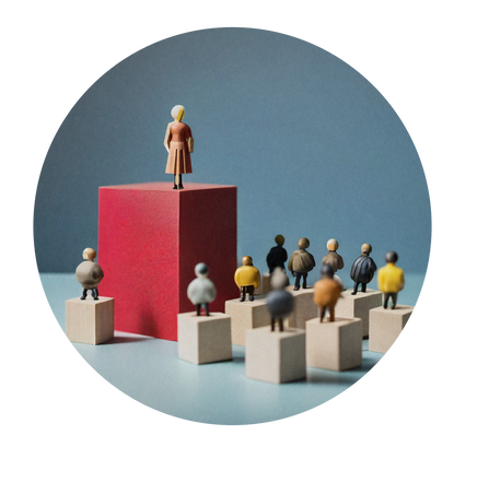 A doll stands on top of a large red block surrounded by smaller dolls on smaller unpainted block